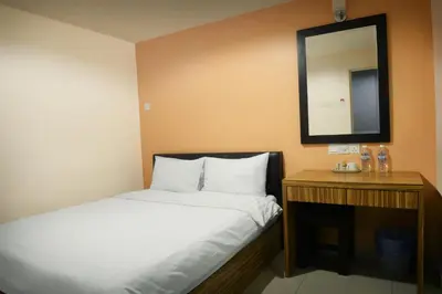 a small bedroom with a bed and a mirror at Brezza Hotel Lumut in Lumut