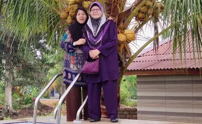 two women standing in front of a palm tree at Kurau Inn Boutique Farmstay in Kuala Kurau