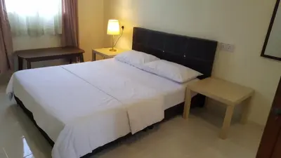 a bedroom with a large white bed and a table at Kurau Inn Boutique Farmstay in Kuala Kurau