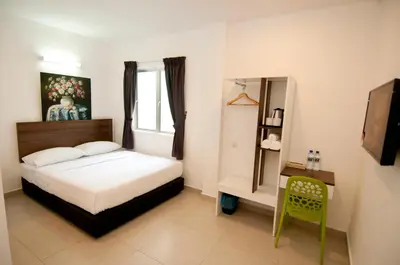 a bedroom with a bed and a table and a chair at Hotel Cheqinn in Ipoh