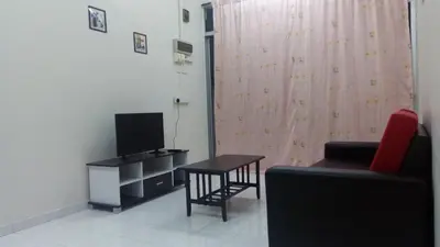 a living room with a tv and a table and a chair at Taiping Vacation Homestay in Taiping