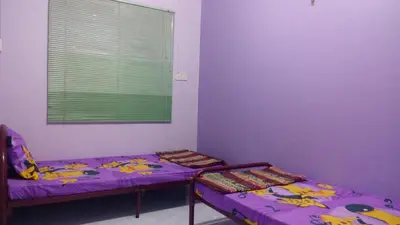 two beds in a room with purple walls and a window at Taiping Vacation Homestay in Taiping