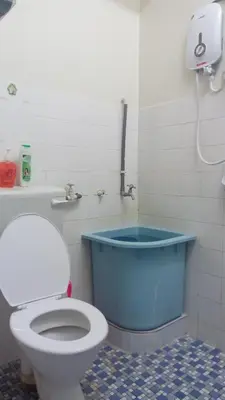 a bathroom with a toilet and a blue tub at Taiping Vacation Homestay in Taiping