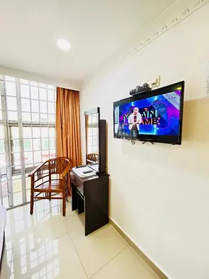 a living room with a tv on a wall at Hotel Sagittario in Ipoh