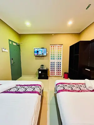 two beds in a room with a tv on the wall at Hotel Sagittario in Ipoh