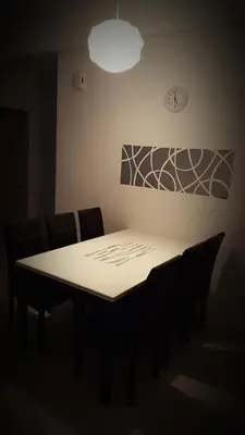 a dining room table with chairs and a clock on the wall at Dephane Apartment in Cameron Highlands