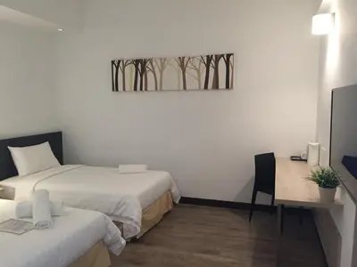 a room with two beds and a desk and a picture at Fuller Hotel Kulim in Kulim