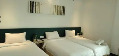 two beds in a room with a green wall at Fuller Hotel Kulim in Kulim