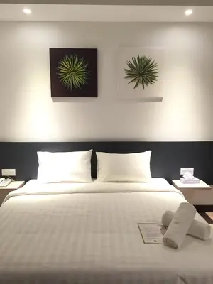 a bedroom with a bed with a baby laying on it at Fuller Hotel Kulim in Kulim