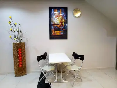 a table and chairs in a room with a painting at Royale Hotel Batu Gajah in Ipoh