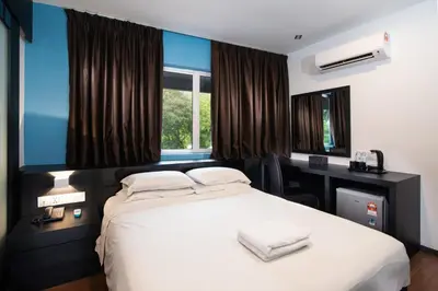 a bedroom with a white bed with a desk and windows at Hotel Waterfall in George Town
