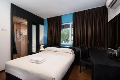 a bedroom with a bed and a desk and a window at Hotel Waterfall in George Town