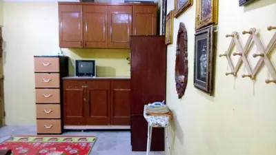 a room with a kitchen with wooden cabinets at Farzai Homestay in Lumut