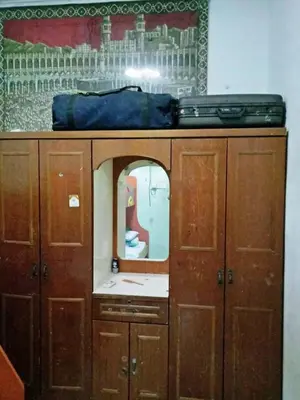 a wooden cabinet with a mirror and a suitcase on top at Farzai Homestay in Lumut