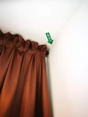 a curtain with a green tag hanging on a wall at Feel Homestay in Cameron Highlands