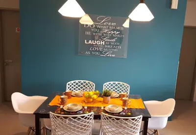 a dining room table with chairs and a blue wall at Feel Homestay in Cameron Highlands