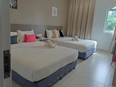 two beds in a hotel room with white walls at Hotel Alpha in Bukit Mertajam