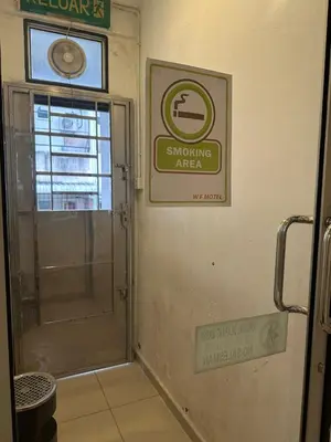 a bathroom with a door and a sign on the wall at WF Motel in Kulim