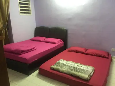 two beds in a room with pink and red sheets at Kak's House Musl!m Only in Ipoh