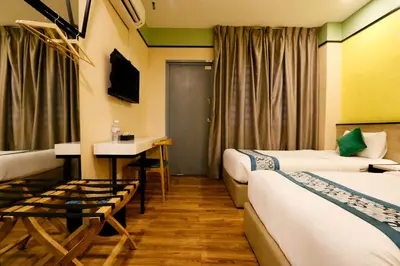 a hotel room with two beds and a desk at Golden Roof Hotel, Seri Iskandar in Seri Iskandar
