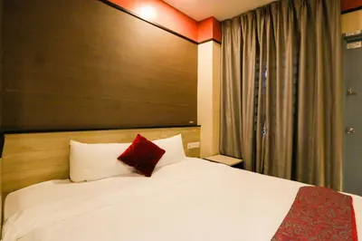 a bedroom with a white bed with a red pillow at Golden Roof Hotel, Seri Iskandar in Seri Iskandar