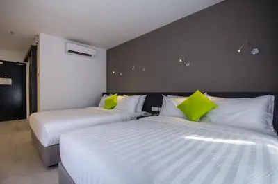 two beds in a hotel room with green pillows at Manhattan Hotel Ipoh in Ipoh