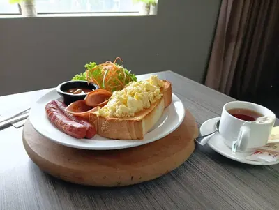 a plate of food with a hot dog and a cup of coffee at Manhattan Hotel Ipoh in Ipoh