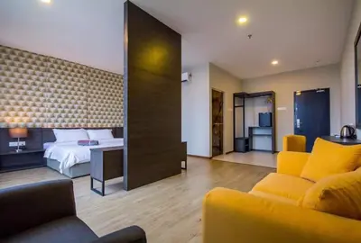 a living room with a bed and a yellow couch at OMG Hotel in Simpang Ampat
