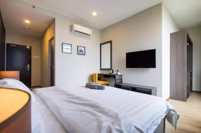 a bedroom with a large white bed and a flat screen tv at OMG Hotel in Simpang Ampat
