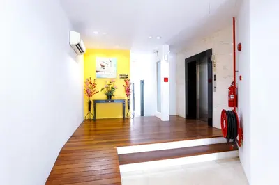 a hallway with wood floors and a yellow wall at Lux Hotel in Teluk Intan