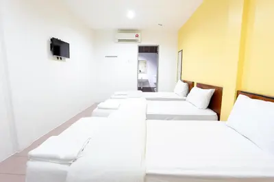 a row of white beds in a room at Lux Hotel in Teluk Intan