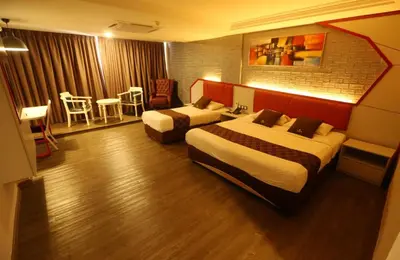 a hotel room with two beds and a table and chairs at Golden Nasmir Hotel in Bukit Mertajam