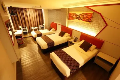 a hotel room with two beds and a table at Golden Nasmir Hotel in Bukit Mertajam