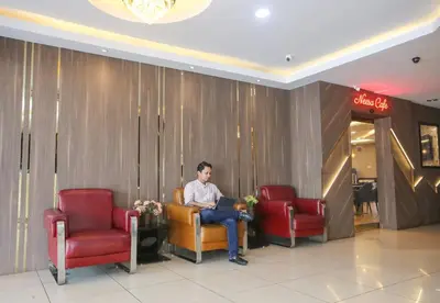 a man sitting in a waiting room with a laptop at Golden Nasmir Hotel in Bukit Mertajam