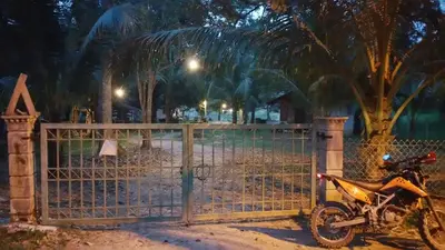 a motorcycle parked next to a gate at night at Chalet Kampong Semawar in Kuala Kangsar