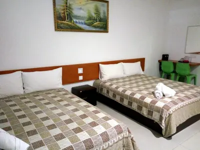 a hotel room with two beds and green chairs at Aloha Hotel in Lumut