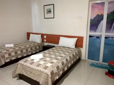 a hotel room with two beds and a window at Aloha Hotel in Lumut