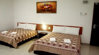 a hotel room with two beds and a painting on the wall at Aloha Hotel in Lumut