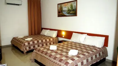 a hotel room with two beds and a picture on the wall at Aloha Hotel in Lumut