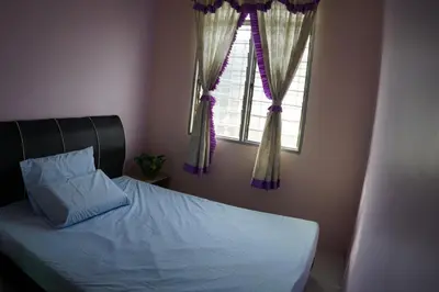 a bedroom with a bed and a window with curtains at Taiping Cozy Homestay in Taiping