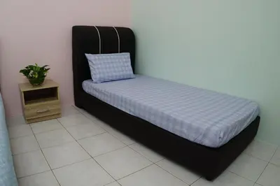 a bed in a room with a pillow and a table at Taiping Cozy Homestay in Taiping