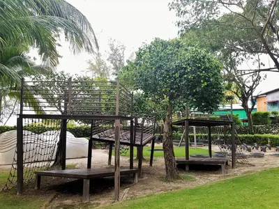 a group of benches in a park with a tree at By The Sea Duplex Condo in Batu Ferringhi