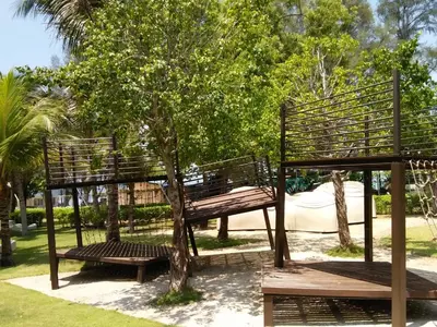 a park with two benches and a tree at By The Sea Duplex Condo in Batu Ferringhi