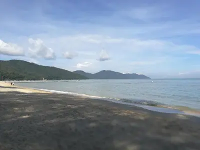 a beach with the ocean and mountains in the background at By The Sea Duplex Condo in Batu Ferringhi