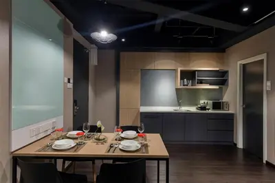 a kitchen with a wooden table with chairs and a dining room at The Granite Luxury Hotel Penang in George Town