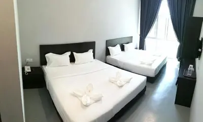 two beds in a hotel room with white flowers on them at JQ BL Hotel, Ipoh in Ipoh