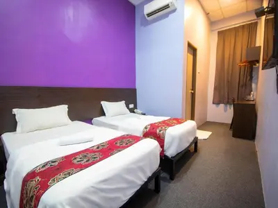 two beds in a room with a purple wall at JQ BL Hotel, Ipoh in Ipoh