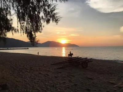a person with a horse on the beach at sunset at By The Sea at Batu Ferringhi Penang in Batu Ferringhi