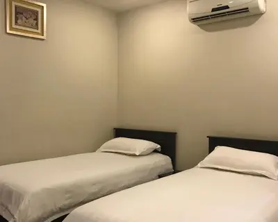 two beds in a room with a air conditioner on the wall at Se One Hotel in Butterworth