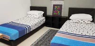 two beds sitting next to each other in a bedroom at Fahaz Lumut Homestay in Lumut